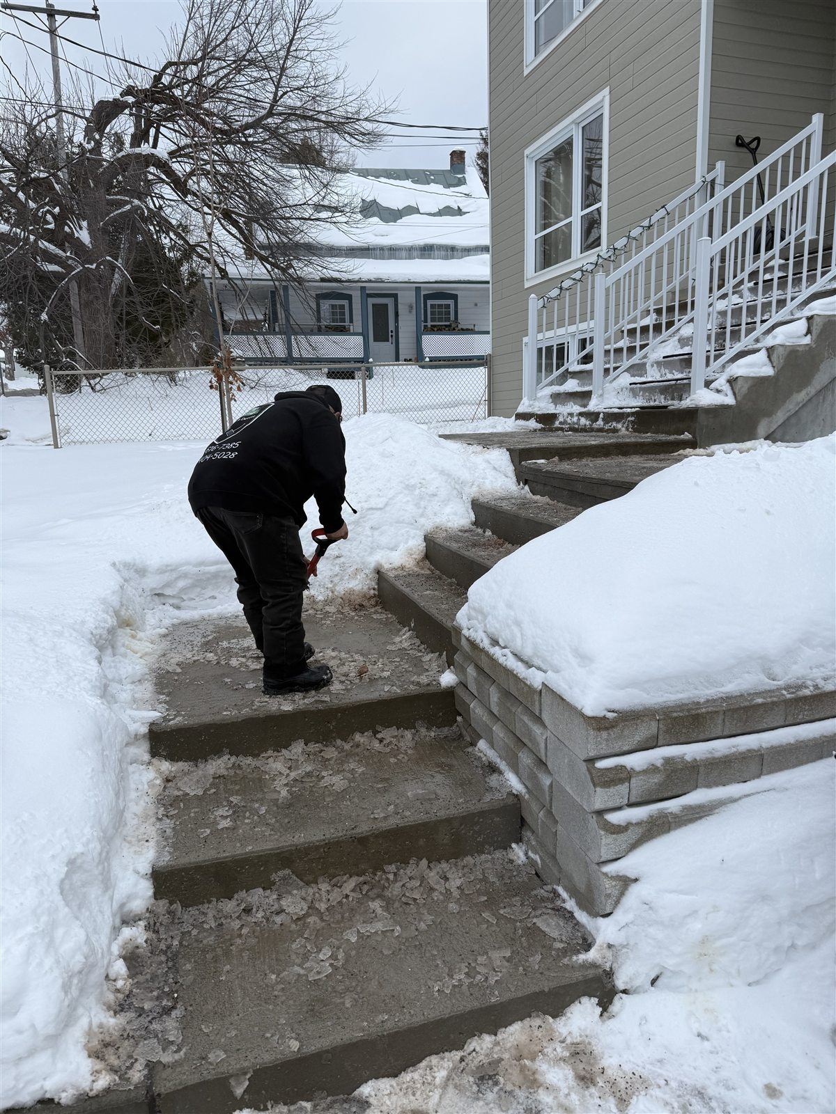 Travailleur déneigeant des marches à la pelle